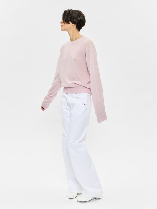 Person wearing a light pink sweater and white pants on a white background