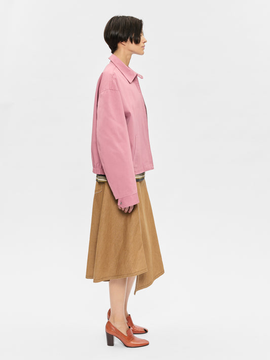 Person wearing a pink shirt and brown skirt on a white background