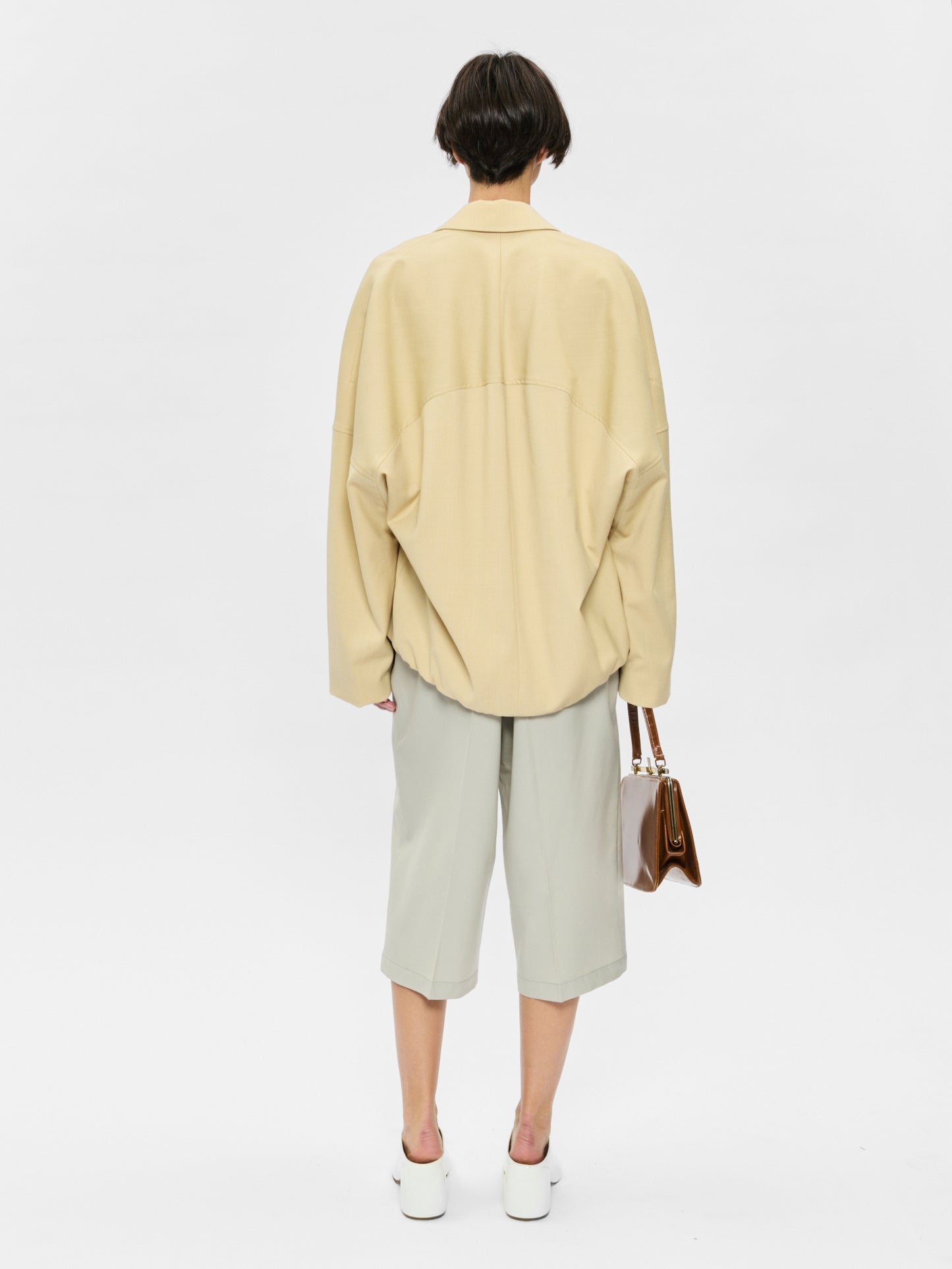 Person wearing a light yellow shirt and light gray pants on a white background