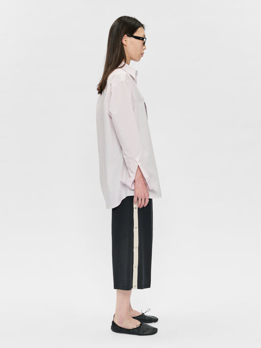 Person wearing a light-colored shirt and black pants on a white background