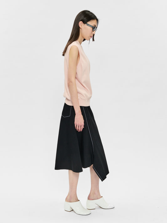 Woman wearing a sleeveless pink top and black skirt on a white background