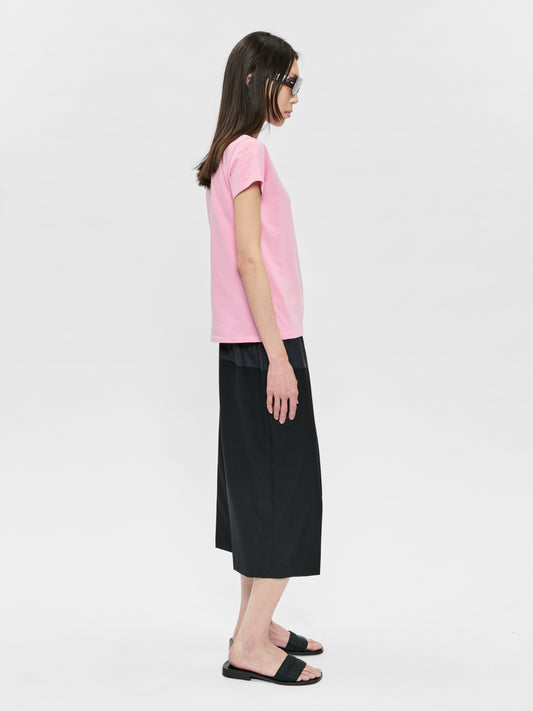 Woman wearing a pink top and black skirt on a white background