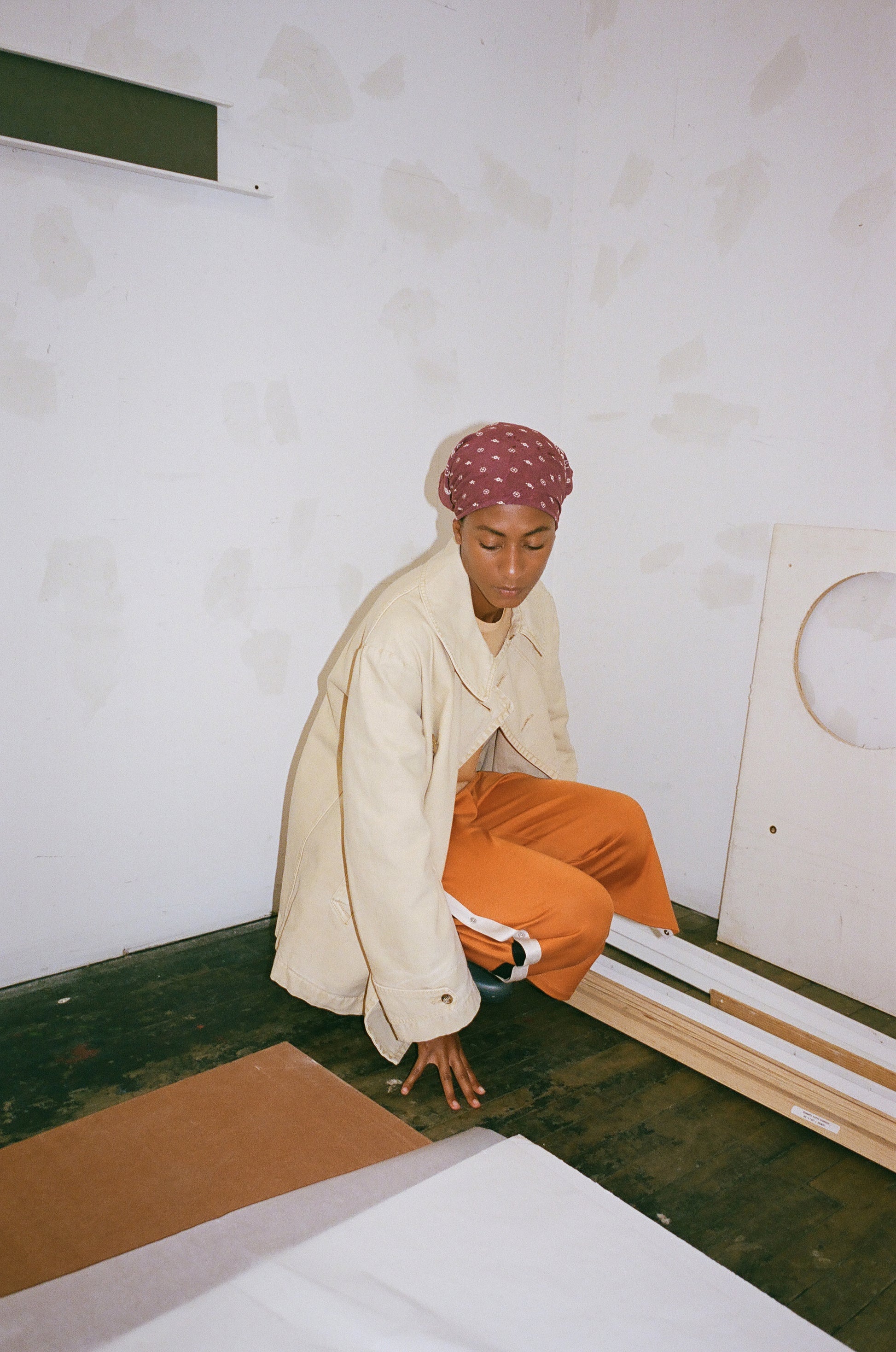 Person sitting on the floor in a minimal room with white walls and green floor.