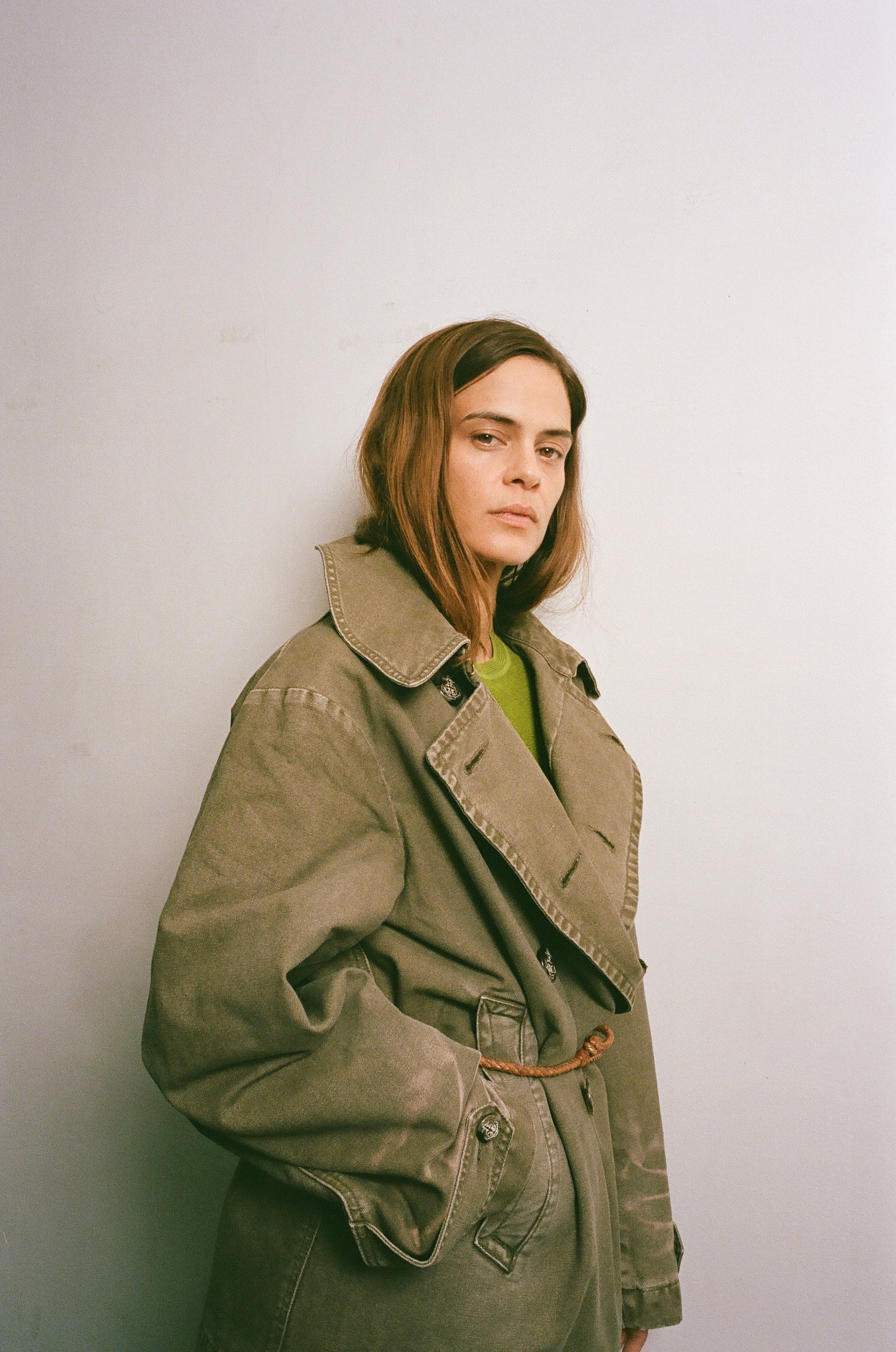 Person wearing a green coat against a plain background