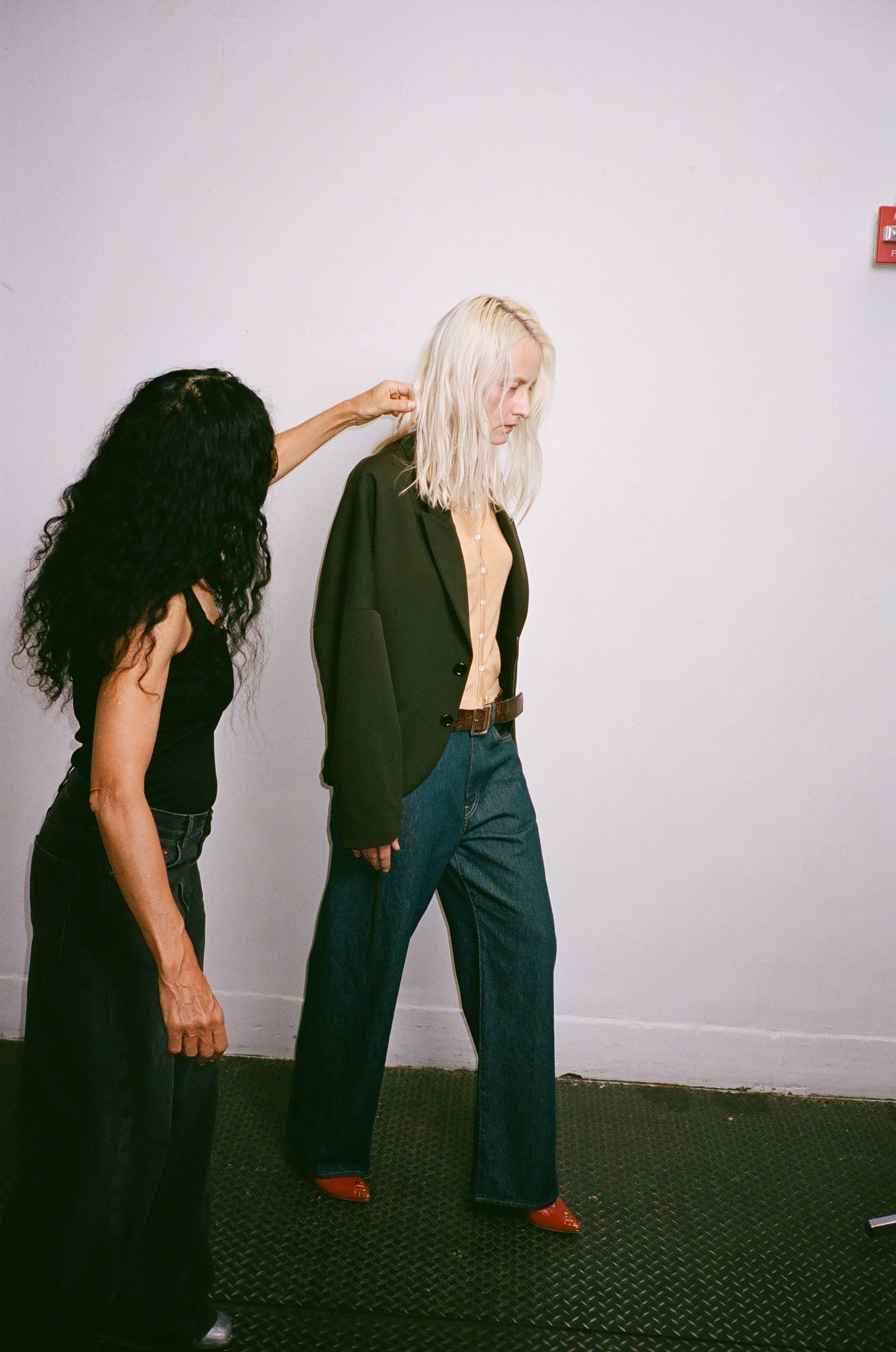 Two people in a room with a plain white wall.