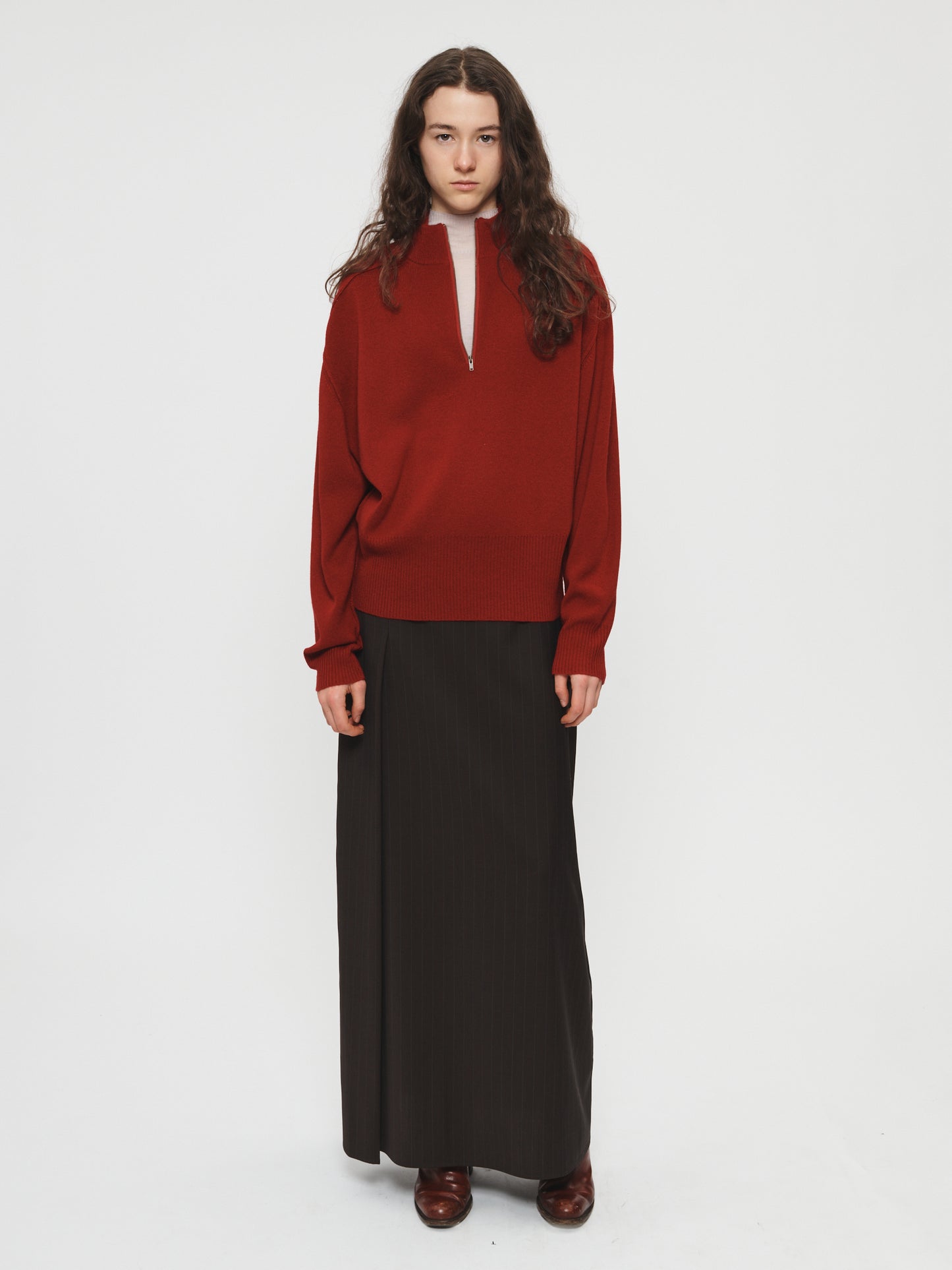 Person wearing a red sweater and black skirt on a white background