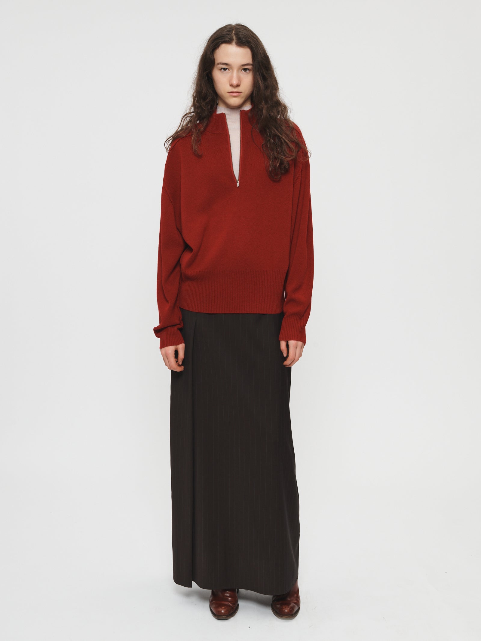 Person wearing a red sweater and black skirt on a white background