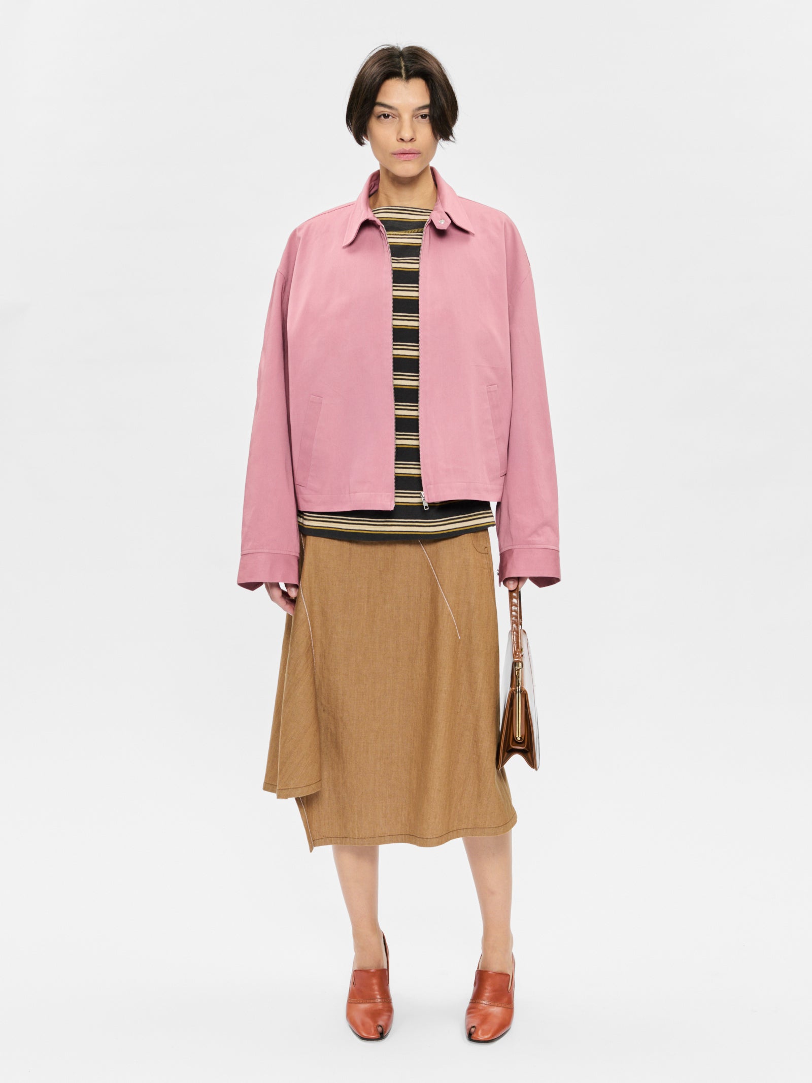 Person wearing a pink jacket, striped shirt, and brown skirt on a white background