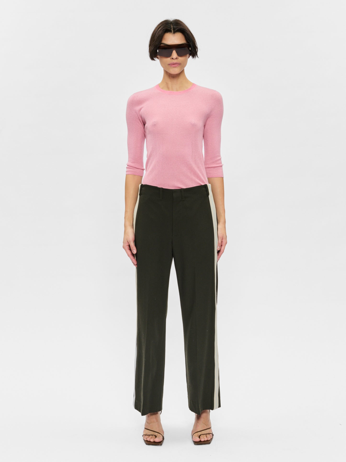 Woman wearing a pink sweater and black pants on a white background