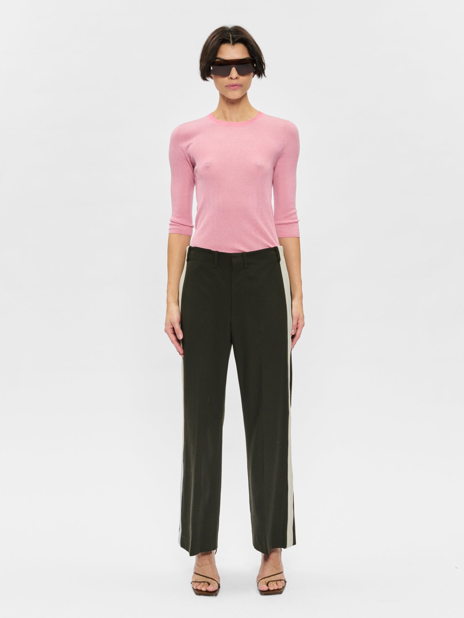 Woman wearing a pink sweater and black pants on a white background