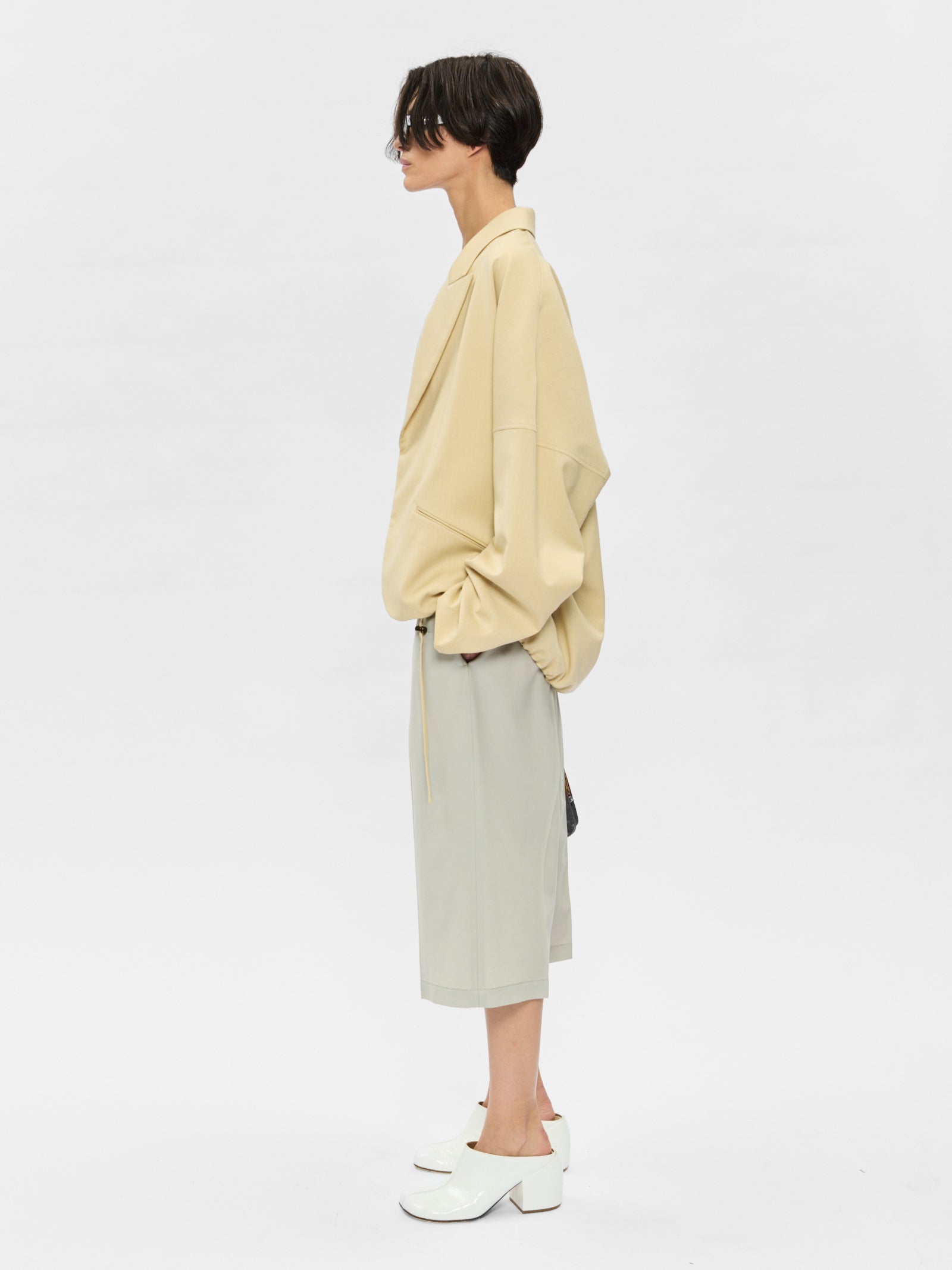 Person wearing a beige shirt and light green skirt on a white background