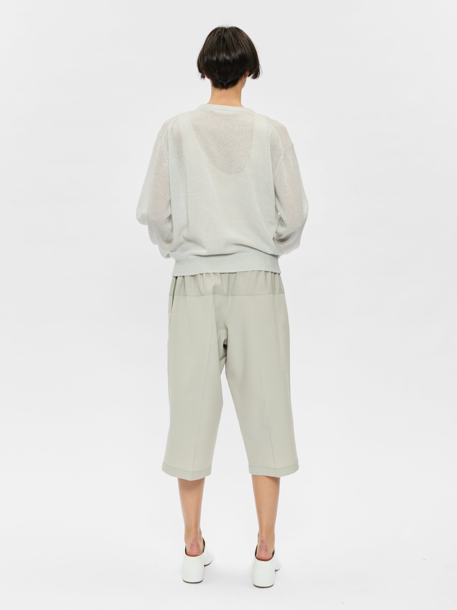 Person wearing a light gray outfit on a white background