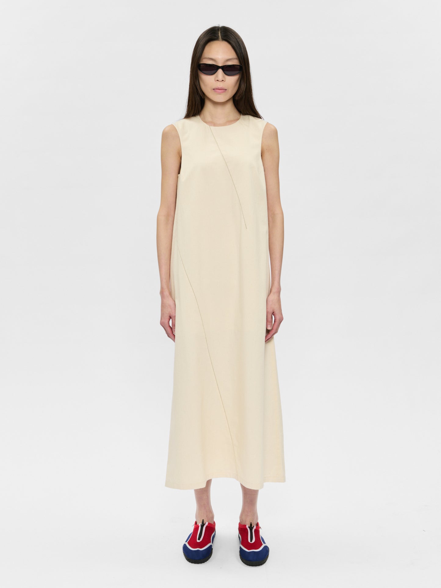 Woman wearing a beige sleeveless dress on a white background