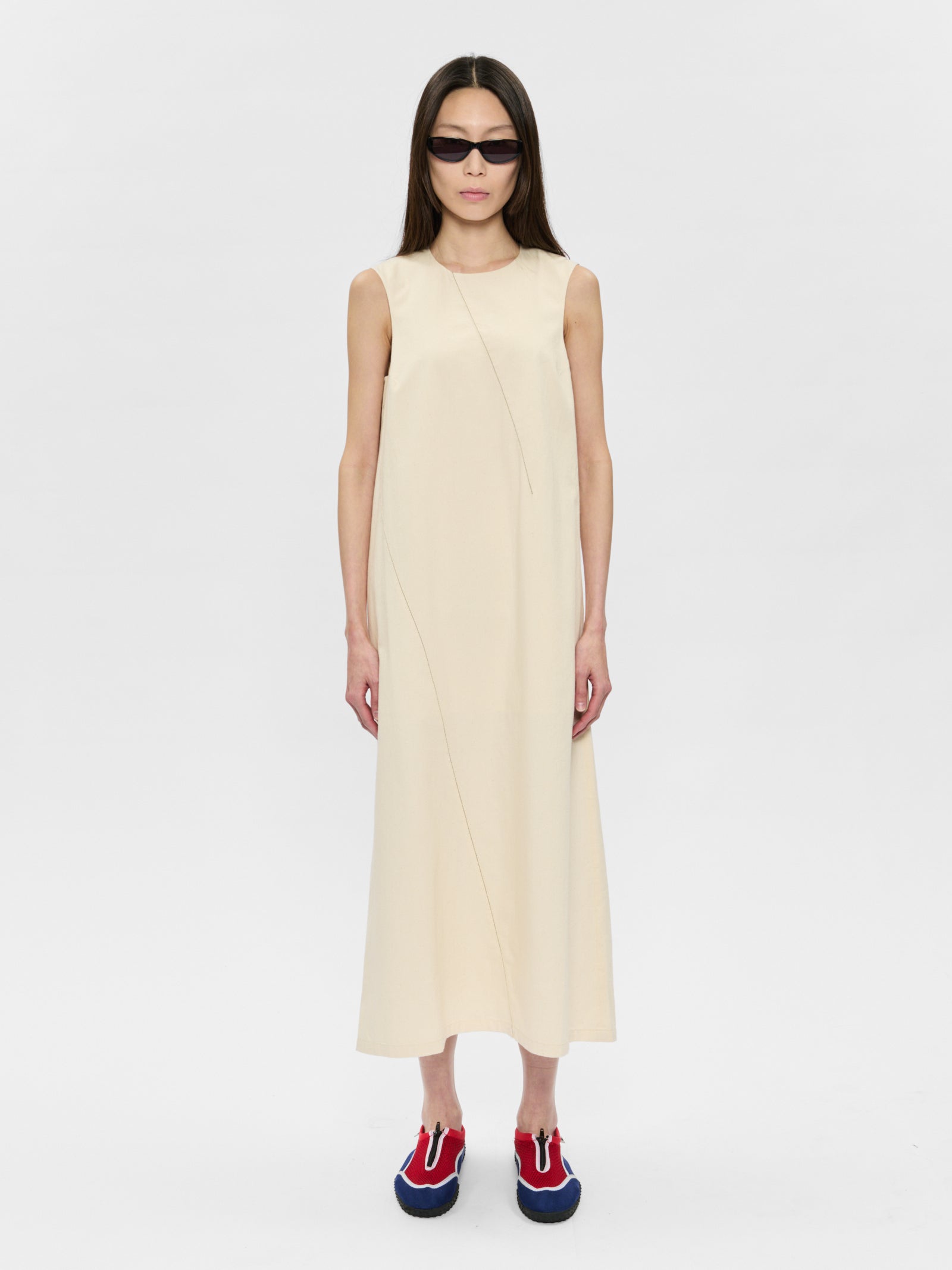 Woman wearing a beige sleeveless dress on a white background