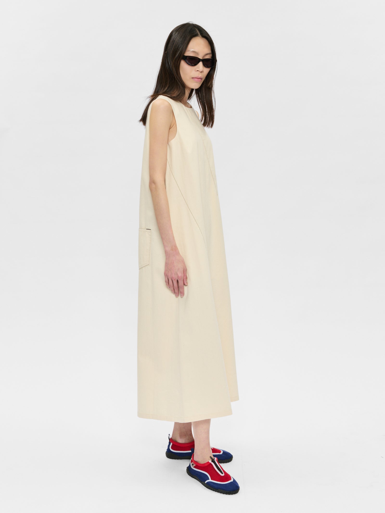 Woman wearing a beige sleeveless dress with colorful shoes on a white background