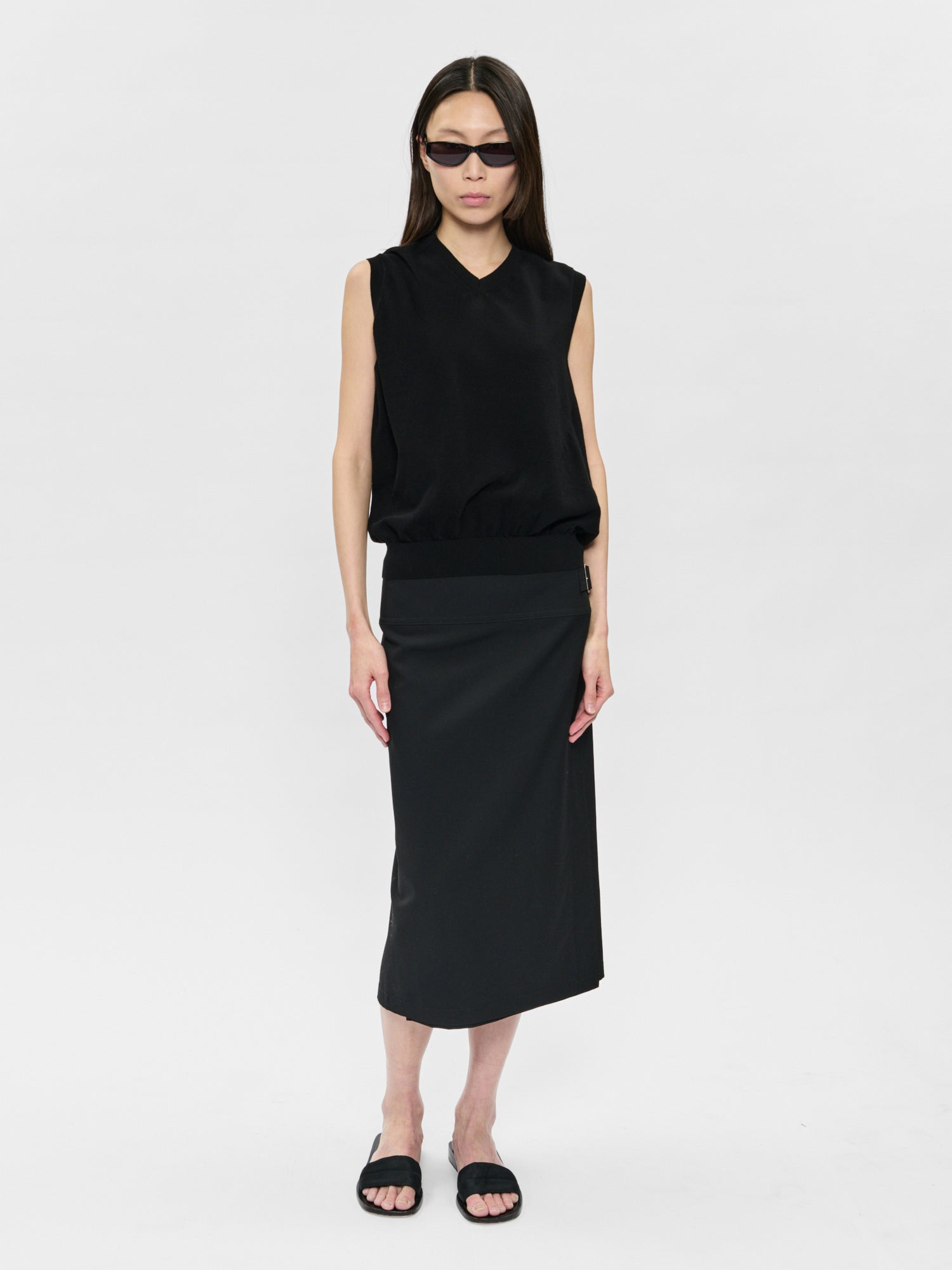Woman wearing a black sleeveless top and skirt on a white background