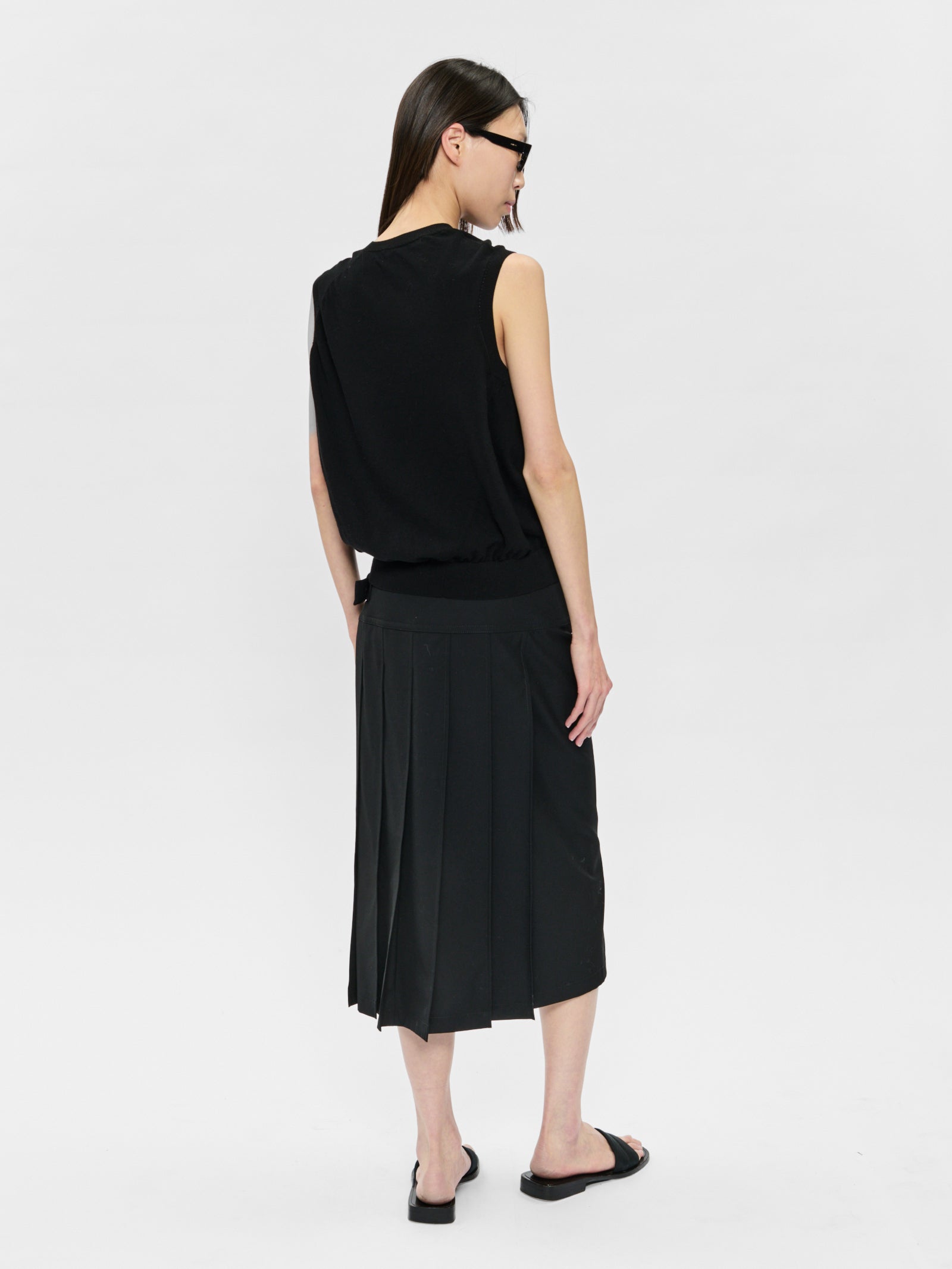 Woman wearing a black sleeveless top and black skirt on a white background