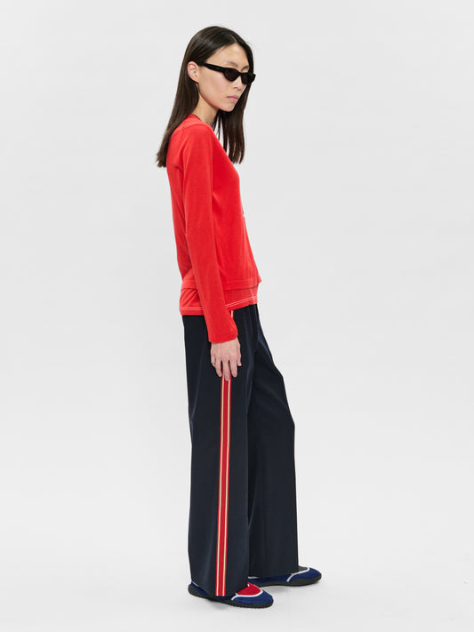 Person wearing a red sweatshirt and black pants with a red stripe on a white background