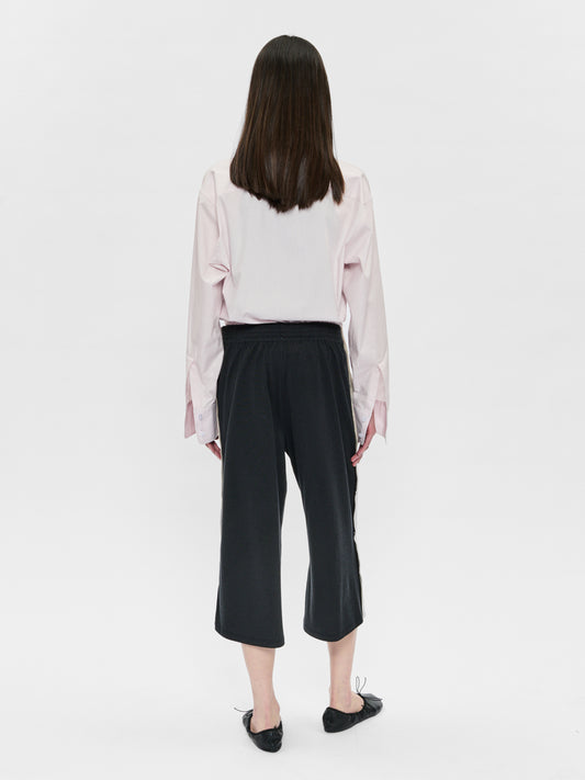 Person wearing a light pink blouse and black pants on a white background