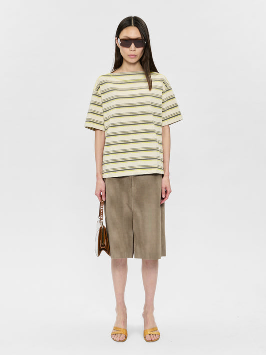Woman wearing a striped shirt and skirt with sunglasses on a white background