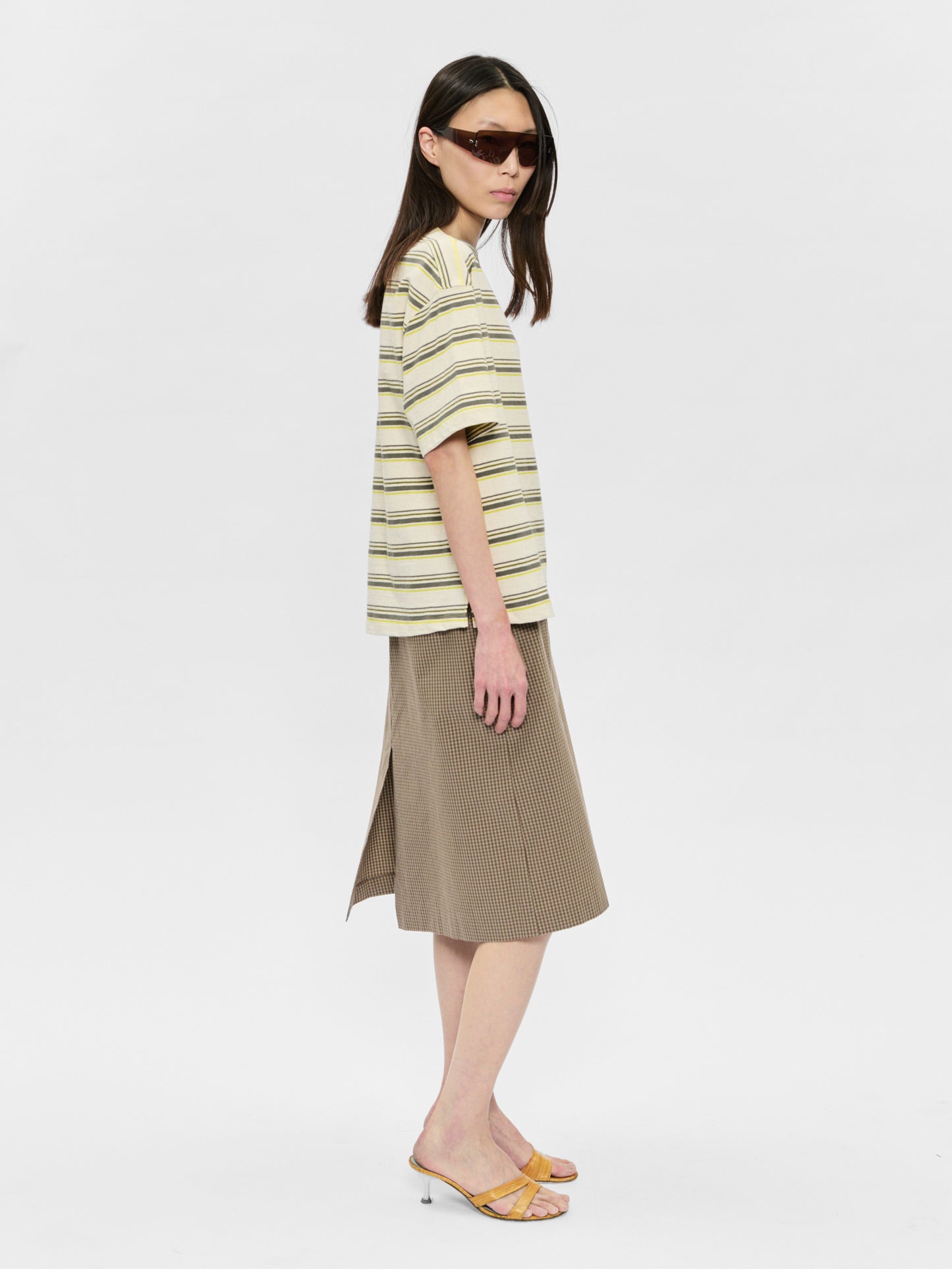 Woman wearing a striped shirt and beige skirt on a white background