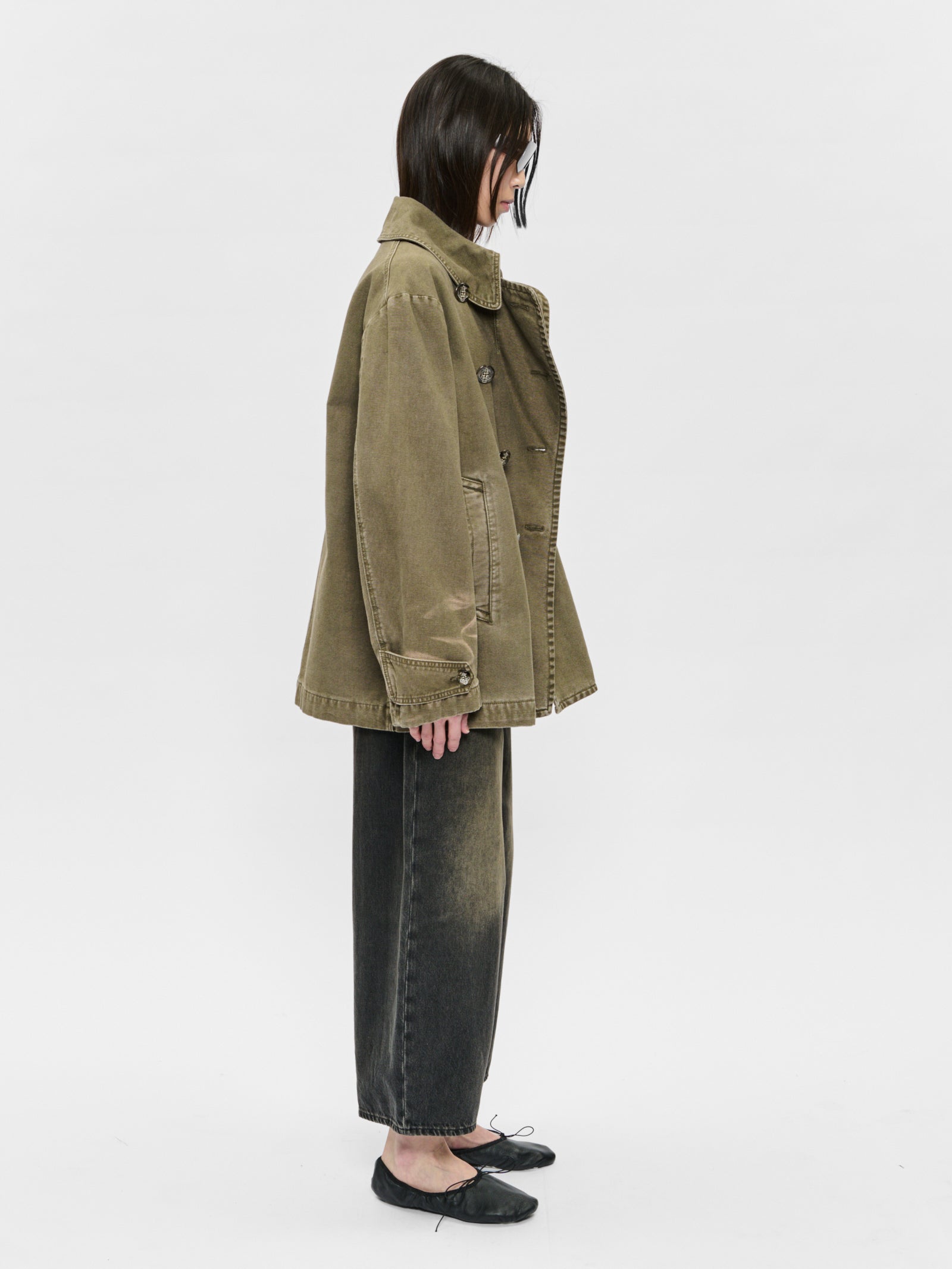 Person wearing a green jacket and black pants on a white background